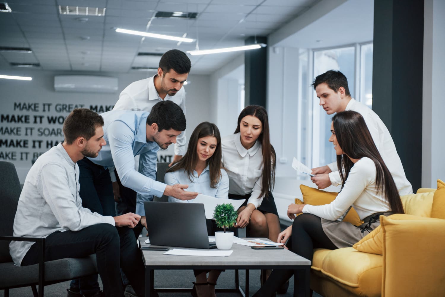 Team huddled around a laptop discussing a project