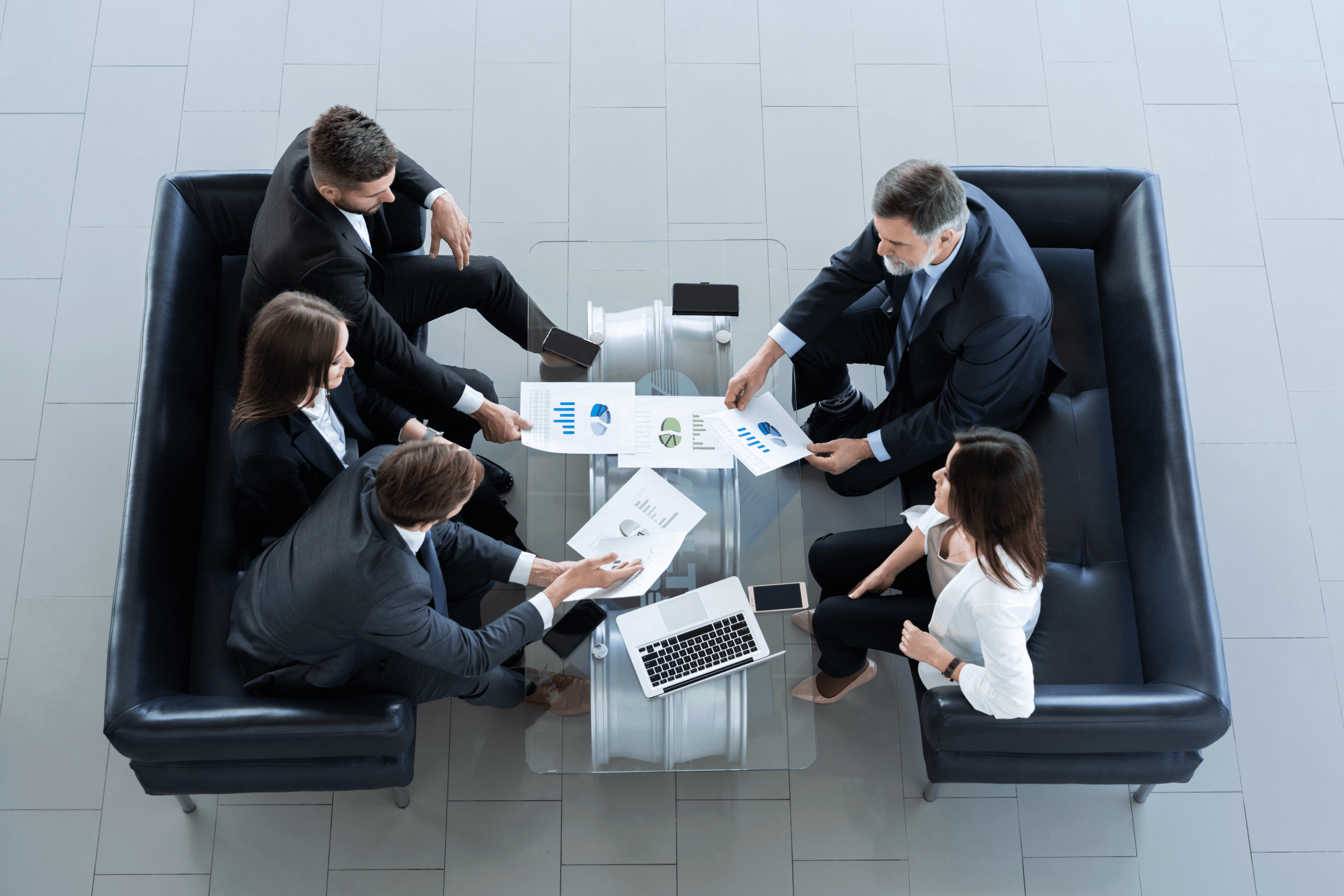 Overhead view of a team reviewing charts and laptops in a meeting